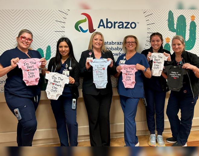 Healthcare staff holding Mother’s Day baby onesies