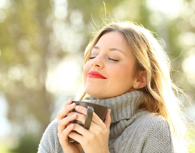 Person holding mug outdoors enjoying sunlight