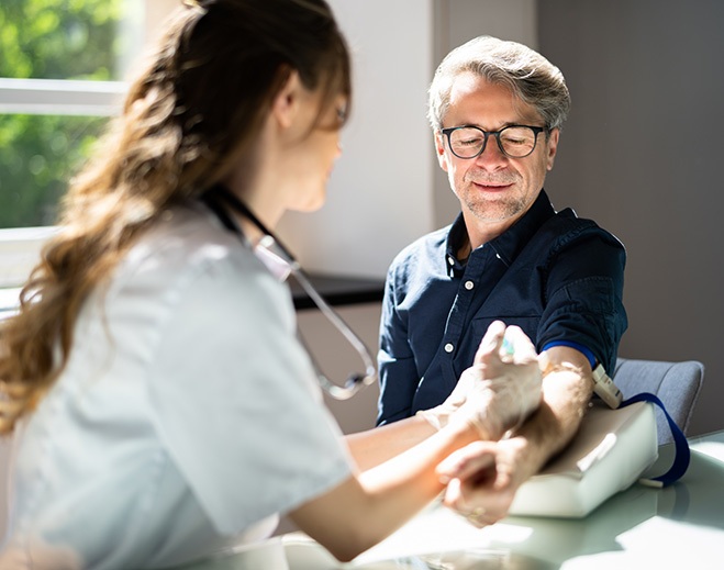 Clinician drawing blood from patient arm