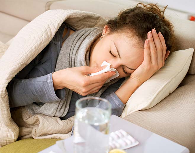 Person lying on couch with cold symptoms
