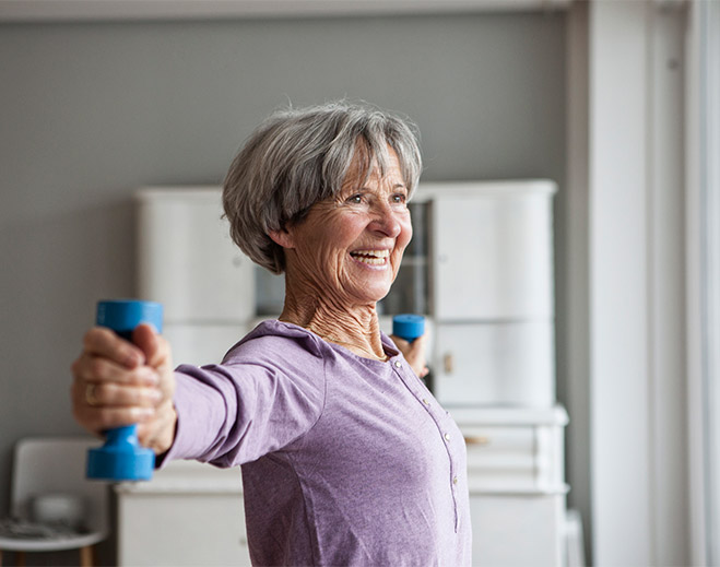 Older adult lifting light dumbbells indoors