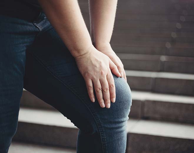 Person holding knee on stairs
