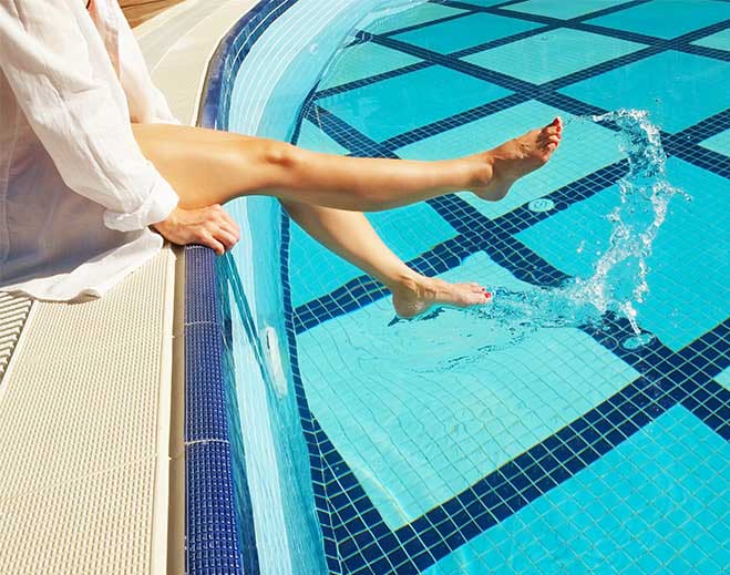 Legs kicking water in swimming pool