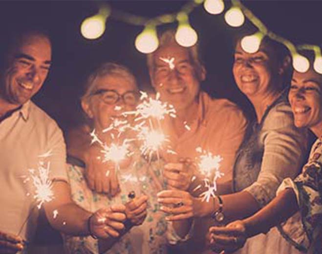 Family smiling and holding burning sparklers