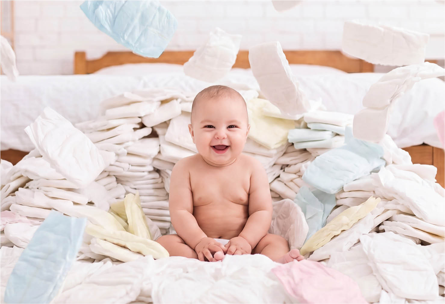 Baby on a bed with piles of diapers