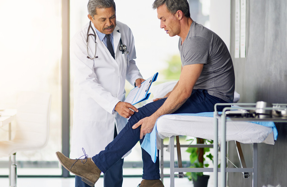 Clinician examining patient’s leg during consultation